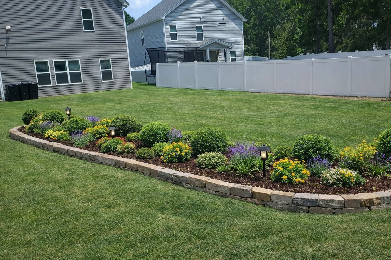 Extended backyard masonry bed with colorful planting groups and finished lawn edges